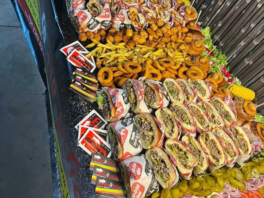 שולחן אירוע ארוך עם כריכים עטופים, טבעות בצל, צ׳יפס וירקות